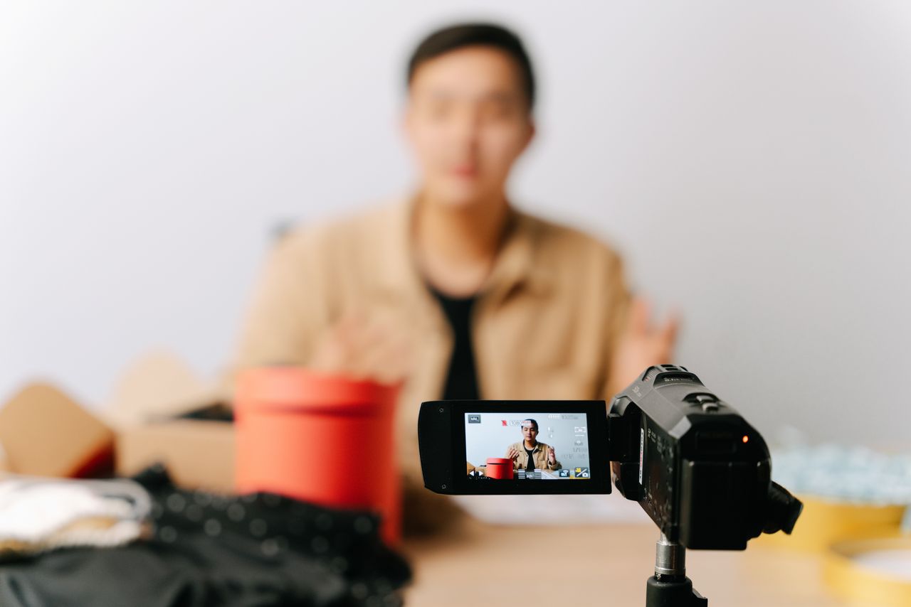 hero-gallery-03 A blogger sits in front of a camera for filming a video indoors.